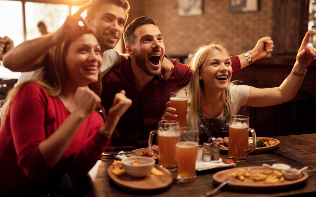group of friends cheering while watching sports at a bar