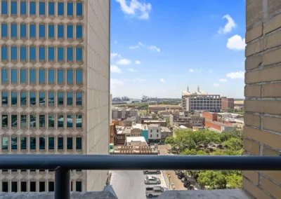 View of a cityscape framed by tall buildings, showing urban structures, trees, and a clear blue sky in the background at Merchants Plaza.