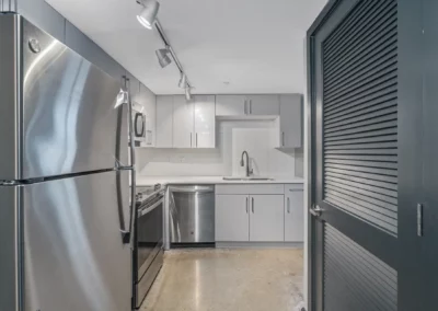 Modern kitchen with stainless steel appliances, including a fridge, stove, microwave, and dishwasher, and gray cabinetry at Merchants Plaza.